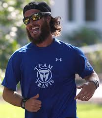 Albie Masland running in a Team Travis shirt, smiling, mid-stride outdoors