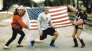 A runner kneeling in front of a large American flag held up by two people